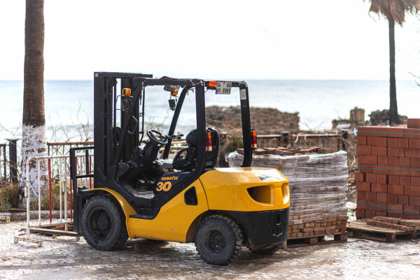 Side, Turkey -January 25, 2022:  yellow forklift   Komatsu is parked  on the street on a warm summer day against the sea